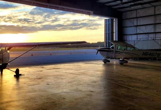 two planes look over the runway into the sunset.